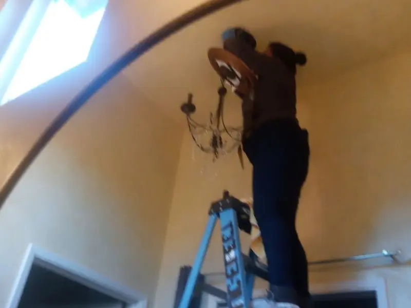 Electrician installing a chandelier in a Canaan residence